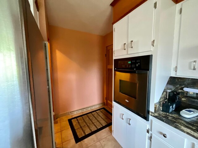 kitchen with wall oven, white cabinetry, light tile patterned flooring, and baseboard heating