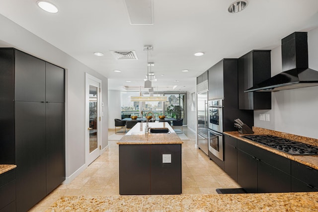 kitchen with pendant lighting, a kitchen island with sink, black gas cooktop, wall chimney range hood, and sink