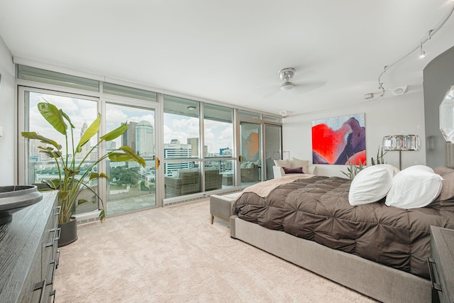 bedroom featuring access to exterior, ceiling fan, expansive windows, track lighting, and light carpet