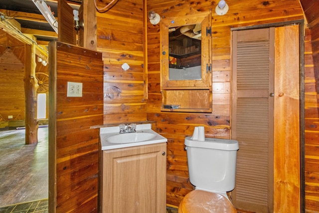 bathroom featuring wooden walls, hardwood / wood-style floors, vanity, and toilet