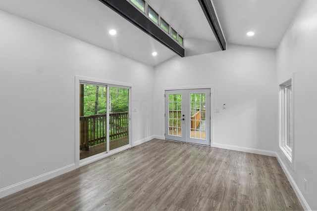 unfurnished room featuring beamed ceiling, plenty of natural light, wood-type flooring, and french doors