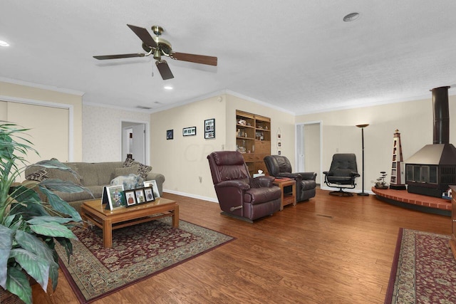 living room featuring hardwood / wood-style floors, a textured ceiling, a wood stove, and ornamental molding