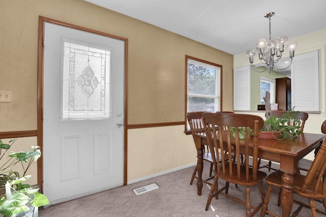 dining area with a notable chandelier and light carpet