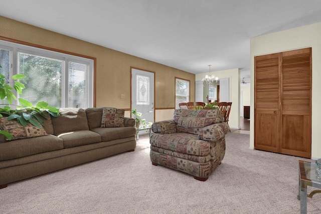 carpeted living room with an inviting chandelier