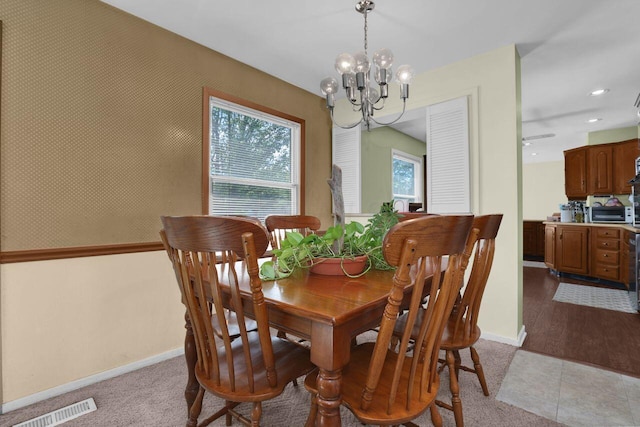 dining space featuring ceiling fan with notable chandelier and light hardwood / wood-style flooring