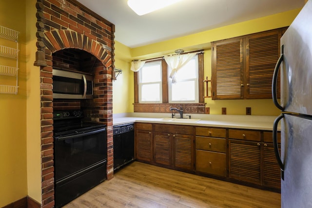 kitchen with light wood-type flooring, sink, and black appliances