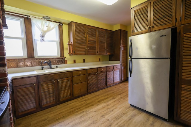 kitchen featuring pendant lighting, sink, light wood-type flooring, and appliances with stainless steel finishes