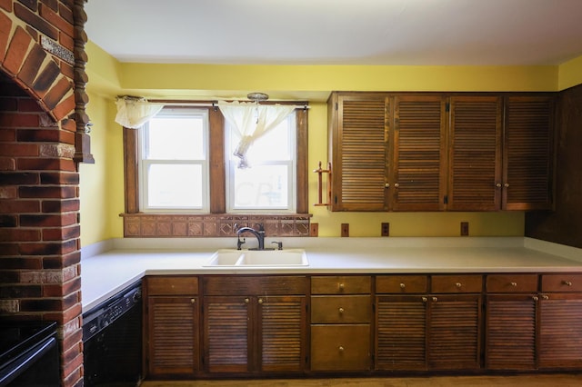 kitchen with dark brown cabinetry, sink, and black dishwasher