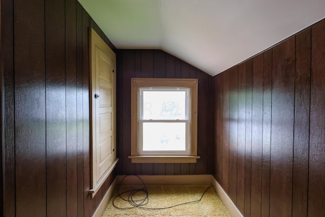 unfurnished room with carpet floors, lofted ceiling, and wood walls