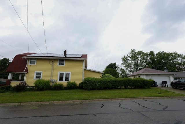 view of side of property with solar panels, a garage, and a lawn