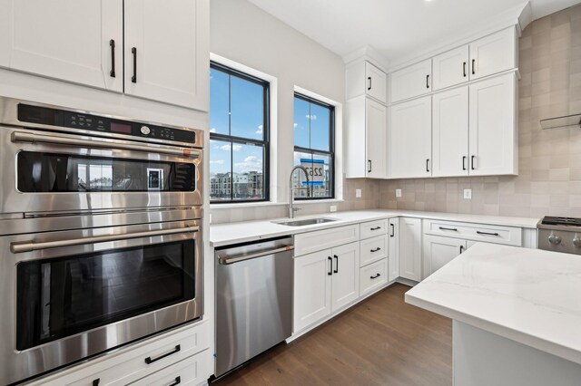 kitchen with tasteful backsplash, sink, white cabinets, stainless steel appliances, and light stone countertops