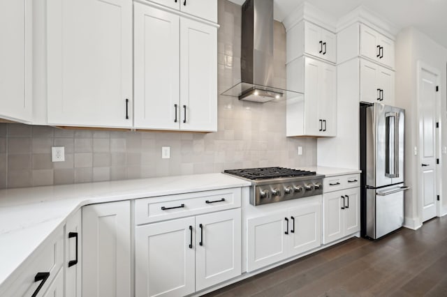 kitchen featuring dark wood-type flooring, white cabinetry, light stone counters, appliances with stainless steel finishes, and wall chimney range hood