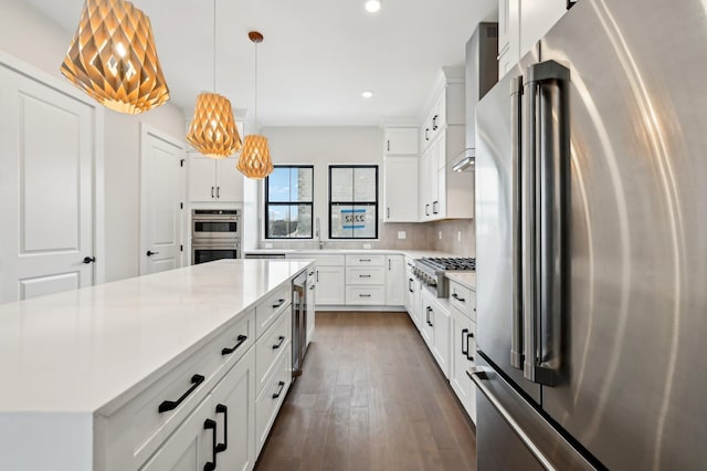 kitchen featuring light stone counters, tasteful backsplash, hanging light fixtures, appliances with stainless steel finishes, and white cabinets