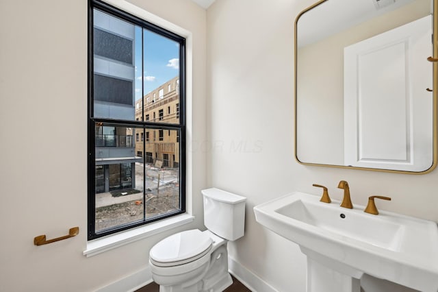 bathroom with a healthy amount of sunlight, sink, and toilet