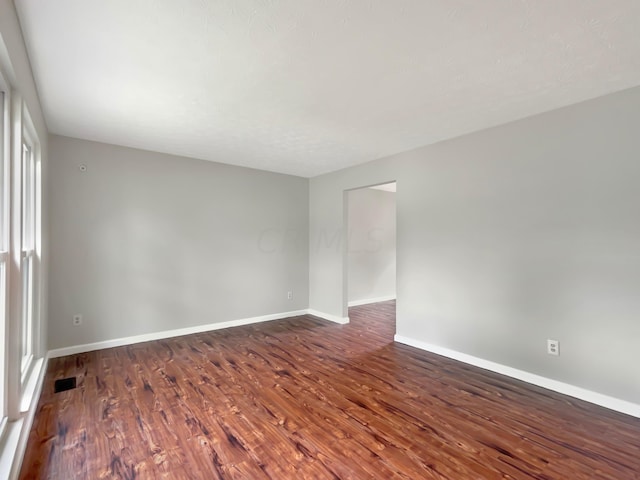 unfurnished room with a healthy amount of sunlight and dark wood-type flooring