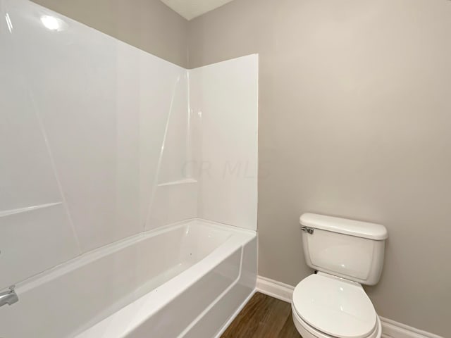 bathroom with shower / washtub combination, toilet, and hardwood / wood-style flooring