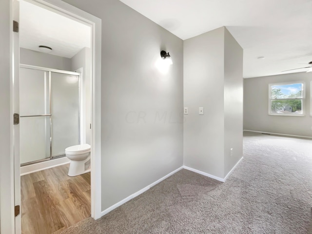 bathroom featuring ceiling fan, toilet, an enclosed shower, and hardwood / wood-style flooring