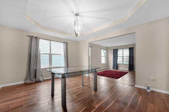 recreation room featuring a textured ceiling, an inviting chandelier, dark hardwood / wood-style floors, and a raised ceiling