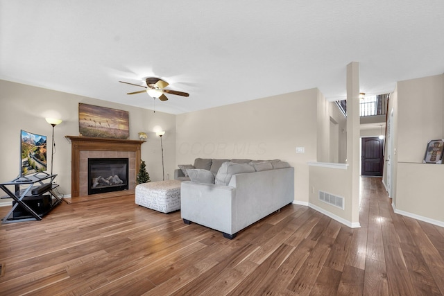 living room featuring ceiling fan, wood-type flooring, and a fireplace