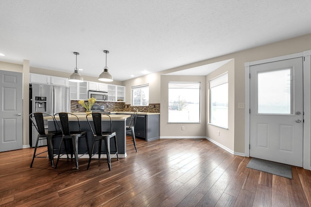 kitchen featuring dark wood-type flooring, pendant lighting, white cabinetry, a kitchen island, and a breakfast bar area