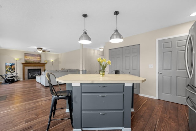 kitchen featuring ceiling fan, dark hardwood / wood-style flooring, stainless steel fridge, decorative light fixtures, and gray cabinets