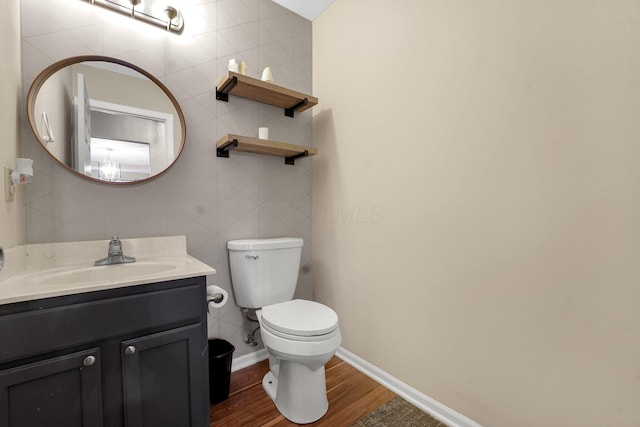 bathroom featuring vanity, hardwood / wood-style flooring, toilet, and tile walls