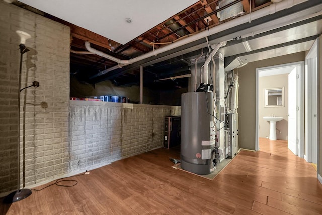 basement featuring hardwood / wood-style floors, sink, and water heater