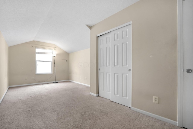 additional living space with light carpet, a textured ceiling, and lofted ceiling