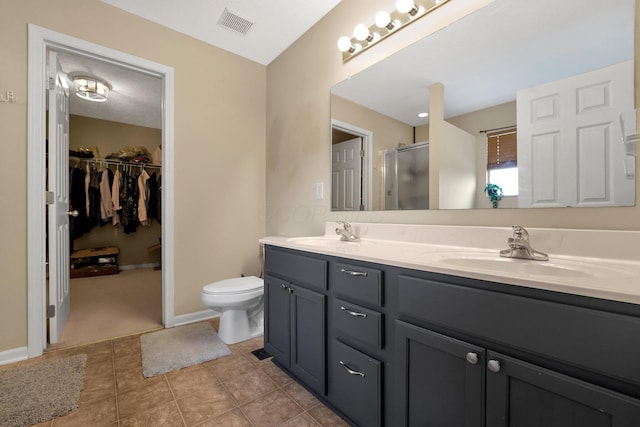 bathroom with tile patterned flooring, vanity, toilet, and walk in shower