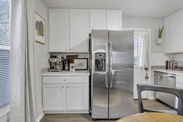 kitchen featuring decorative backsplash, white cabinets, light hardwood / wood-style floors, and appliances with stainless steel finishes