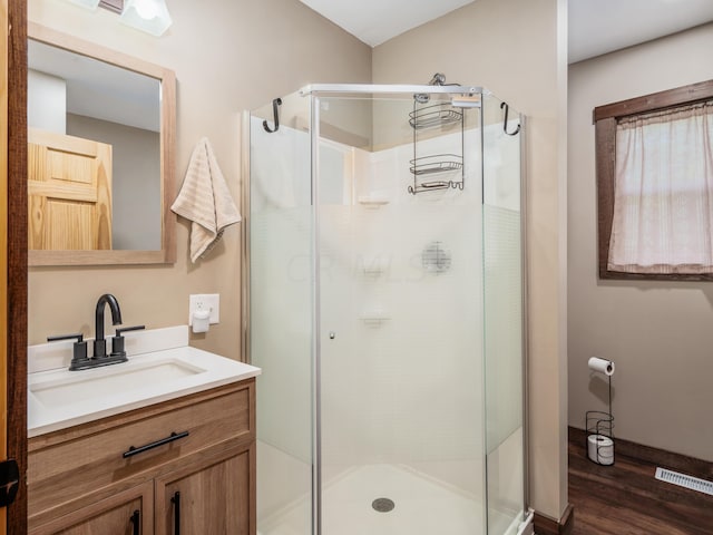 bathroom featuring hardwood / wood-style floors, vanity, and a shower with shower door