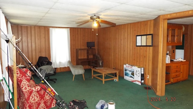 interior space with carpet flooring, ceiling fan, wood walls, and a drop ceiling