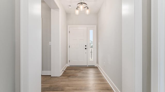 entryway featuring hardwood / wood-style flooring and a chandelier