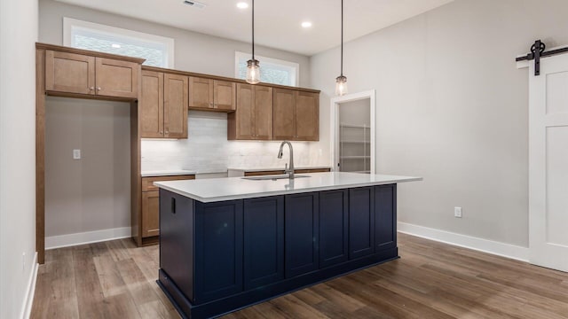 kitchen featuring pendant lighting, sink, dark hardwood / wood-style flooring, a kitchen island with sink, and a barn door