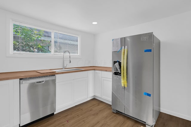 kitchen with a wealth of natural light, white cabinetry, sink, wooden counters, and appliances with stainless steel finishes