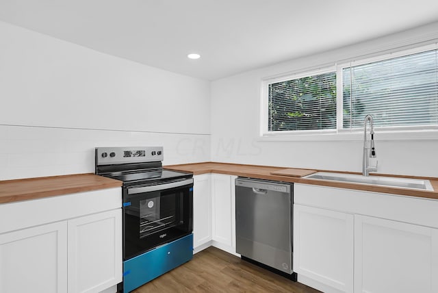 kitchen featuring wooden counters, stainless steel appliances, dark wood-type flooring, sink, and white cabinets