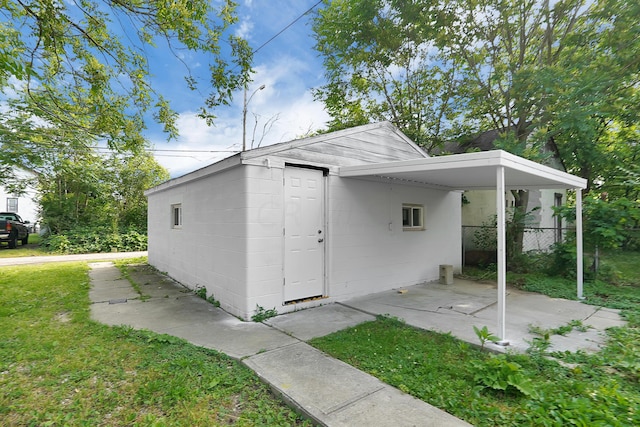 view of outdoor structure with a carport and a lawn