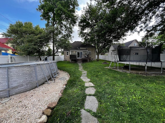 view of yard with an empty pool and a trampoline