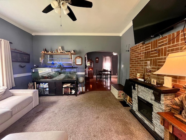 carpeted living room with a fireplace, ceiling fan, crown molding, and track lighting