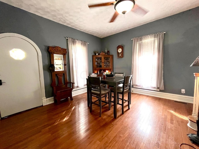 dining room featuring baseboard heating, ceiling fan, a textured ceiling, and dark hardwood / wood-style floors