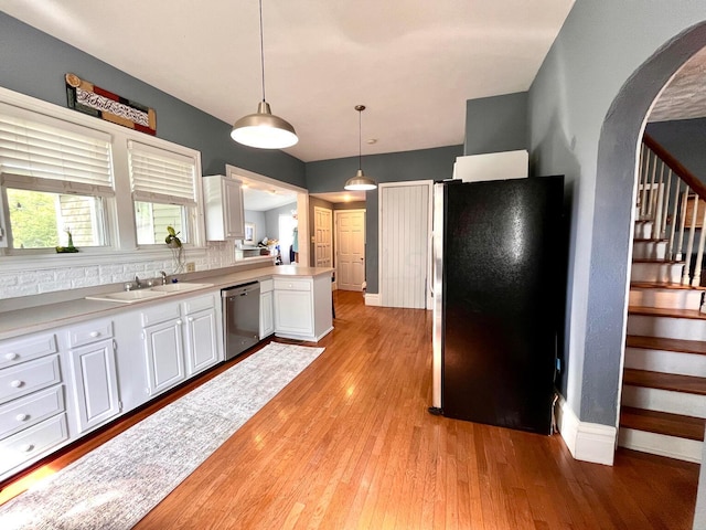 kitchen featuring dishwasher, hanging light fixtures, light hardwood / wood-style flooring, refrigerator, and white cabinets