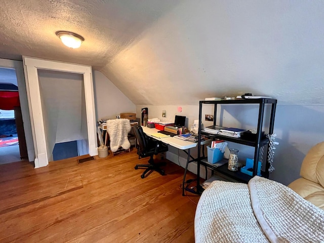 home office with lofted ceiling, wood-type flooring, and a textured ceiling