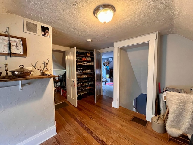 corridor with hardwood / wood-style floors and a textured ceiling