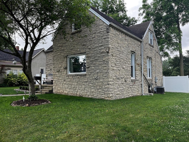 view of side of home with a lawn and cooling unit