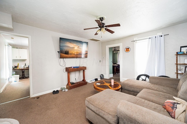 living room with carpet flooring, a textured ceiling, and ceiling fan