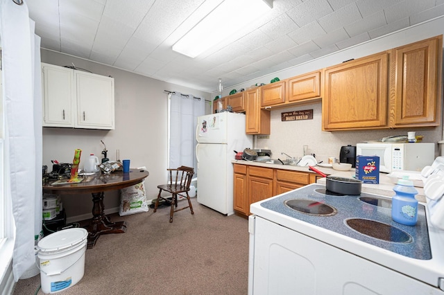 kitchen with white appliances, sink, and light carpet