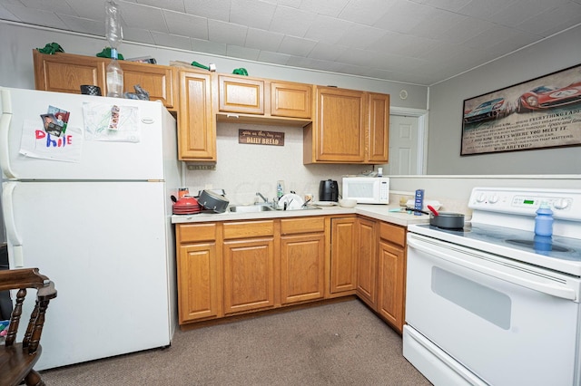 kitchen with sink, white appliances, and light carpet