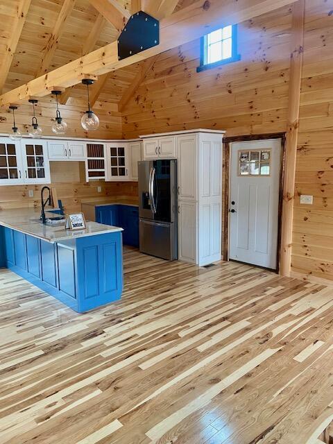 kitchen with pendant lighting, stainless steel fridge, white cabinetry, and light hardwood / wood-style floors