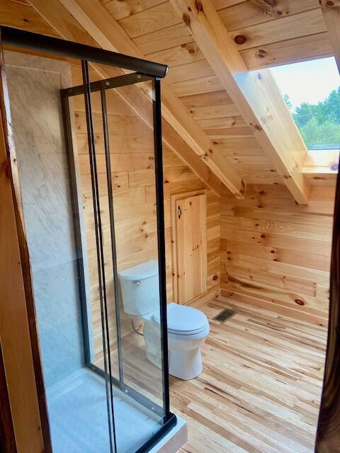 bonus room featuring wood walls, a skylight, hardwood / wood-style flooring, beamed ceiling, and wood ceiling