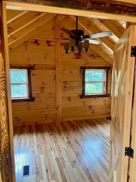 additional living space featuring lofted ceiling with beams, wooden walls, hardwood / wood-style flooring, ceiling fan, and wood ceiling